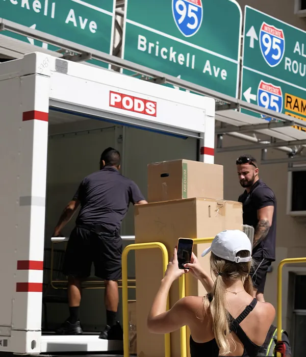 305 Pro Movers crew loading boxes into a PODS container under the Brickell Avenue signs