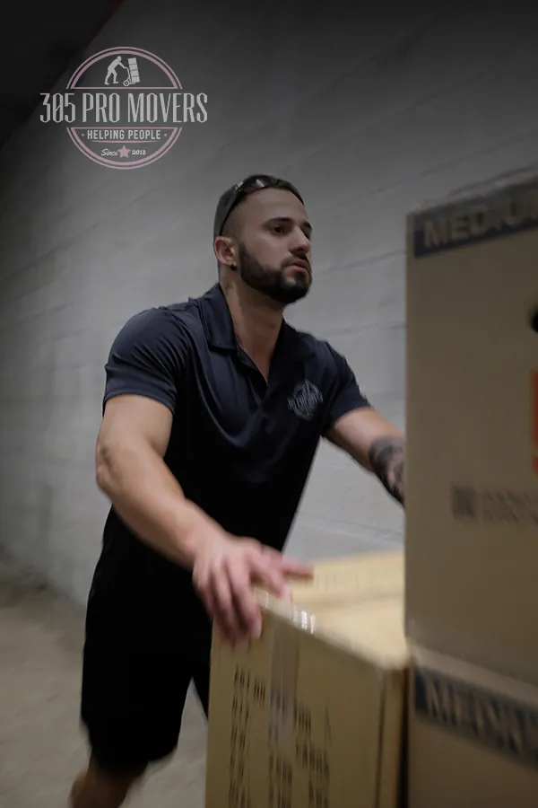305 Pro Movers mover in a company polo pushing stacked boxes