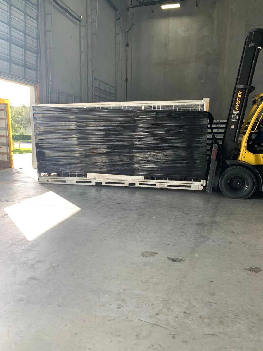Forklift carrying a large shrink-wrapped load in a warehouse