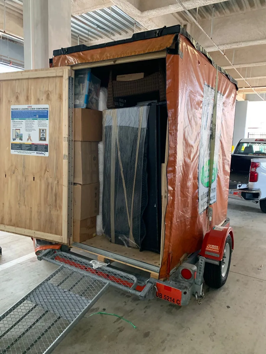 Open moving trailer packed with boxes and wrapped furniture