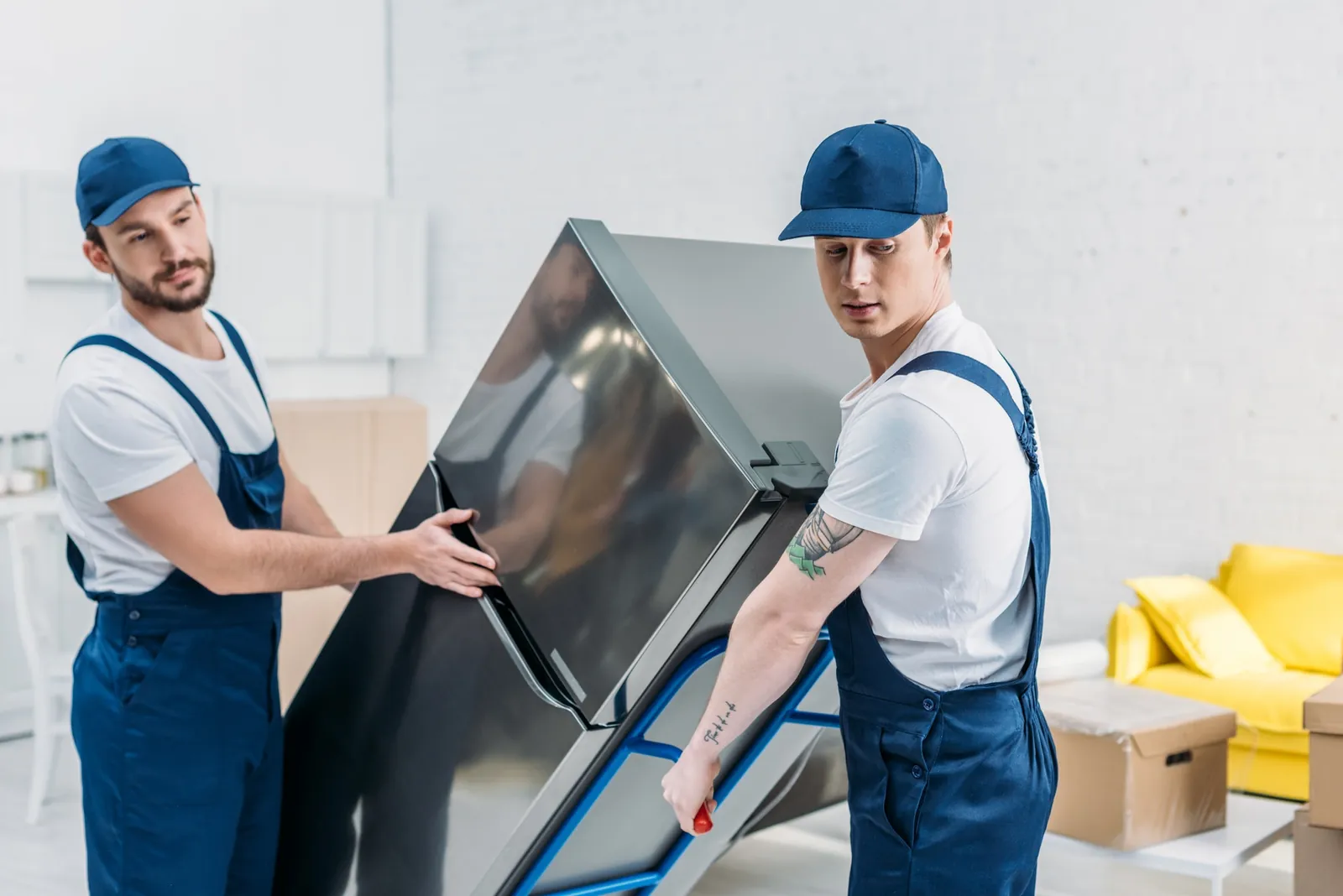 Two movers moving a refrigerator on a hand truck